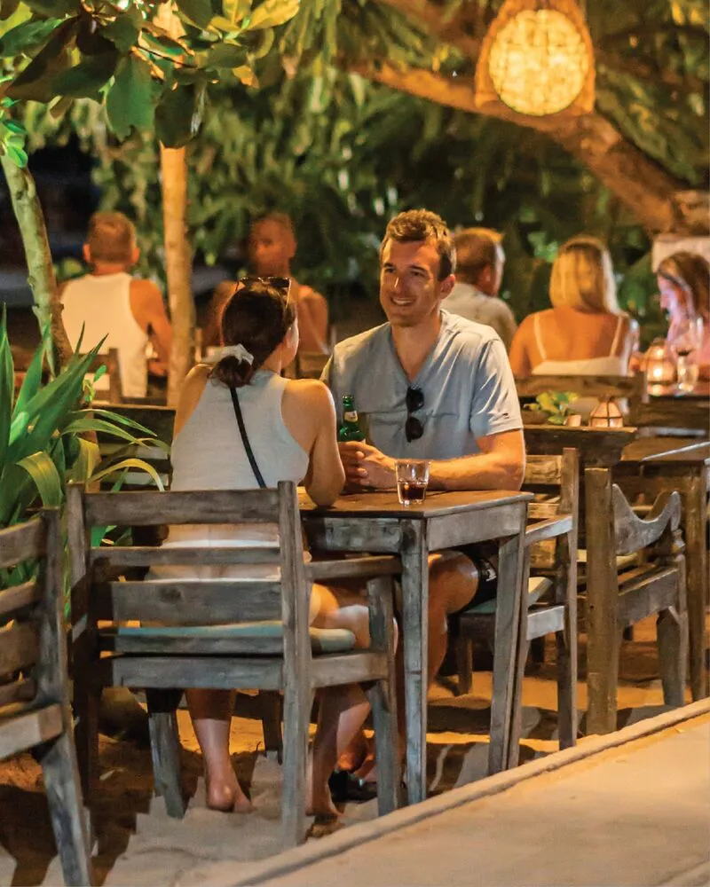 Friends laughing over dinner in the Lilla Warung garden